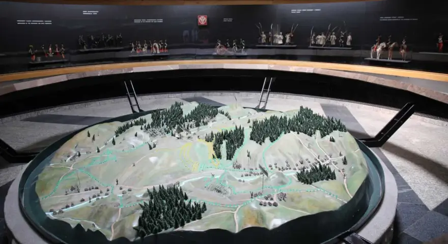 Model terenu przedstawiający bitwę pod Racławicami. Na tle miniatury żołnierzyków w historycznych strojach.