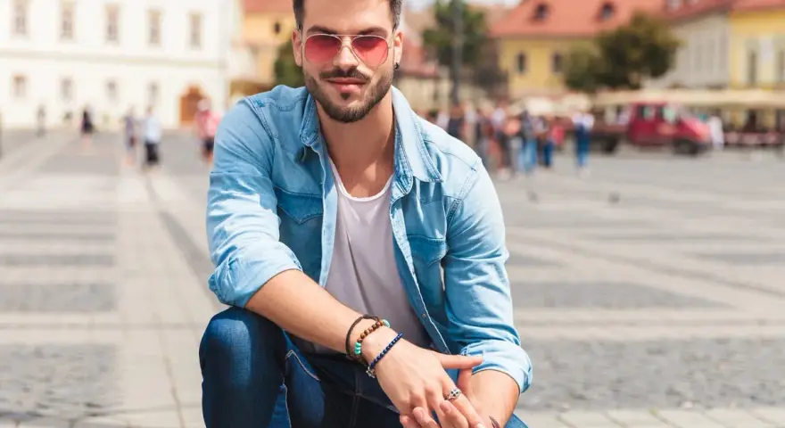 Uomo con occhiali da sole rosa e camicia di jeans, un'idea su come vestirsi in primavera uomo.
