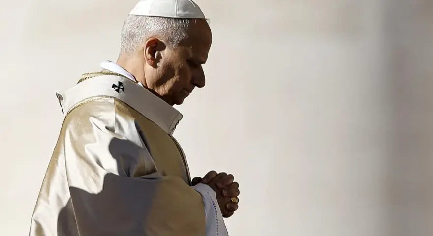 Papież w białej piusce i złotej szacie modli się, wierzę w boga. W jego oczach widać głęboką wiarę.