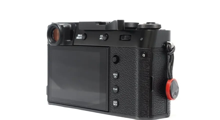 Czarne body aparatu Fujifilm X100S z widocznym ekranem, przyciskami i uchwytem na pasek.