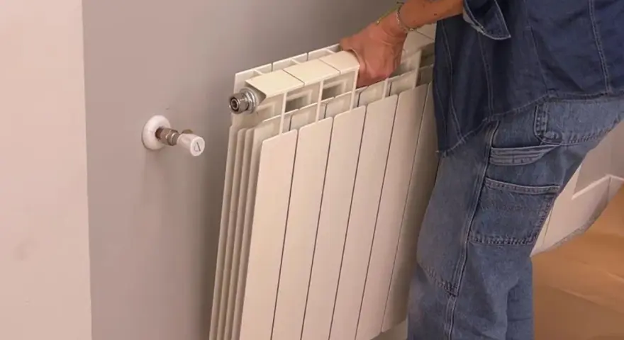 Persona quitando radiadores para pintar la pared.