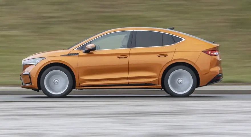 Pomarańczowy elektryczny SUV coupe w ruchu, widok z boku.