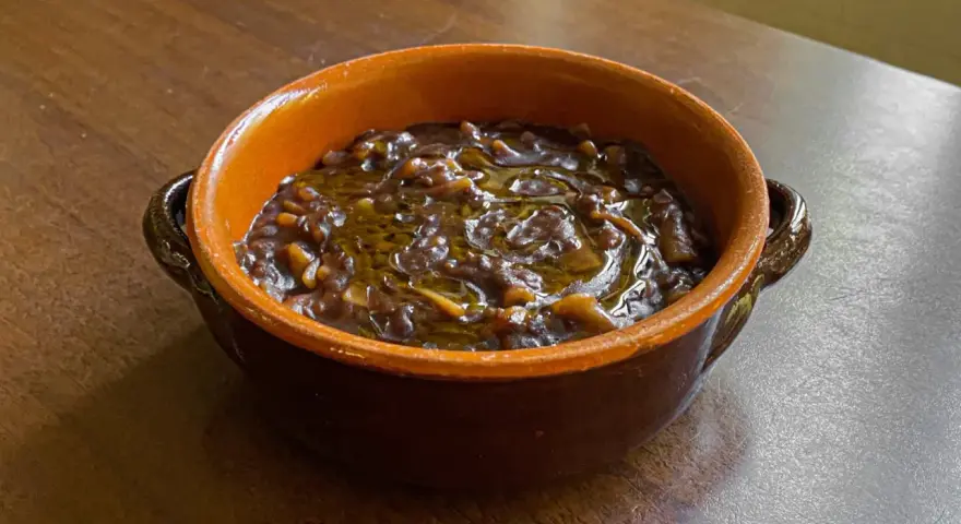 Una ciotola di terracotta con un saporito piatto di pasta e lenticchie, condito con olio d'oliva.