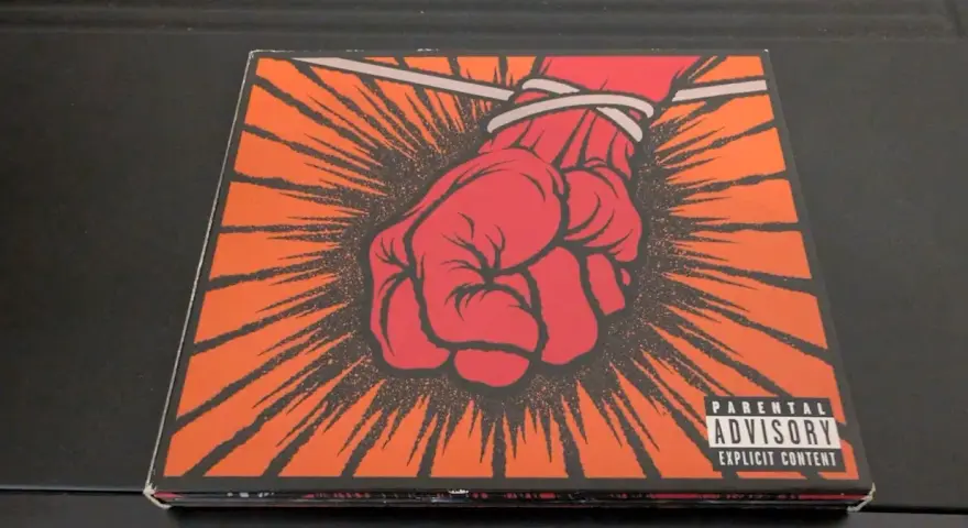 Okładka płyty Metallica "St. Anger" z czerwoną, zawiązaną pięścią i napisem "Parental Advisory".