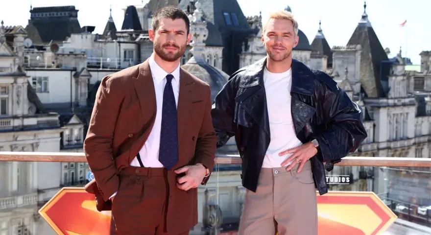Due uomini posano con stile: uno in completo marrone, dimostrando come abbinare il marrone uomo con eleganza, l'altro con giacca di pelle e pantaloni chiari.