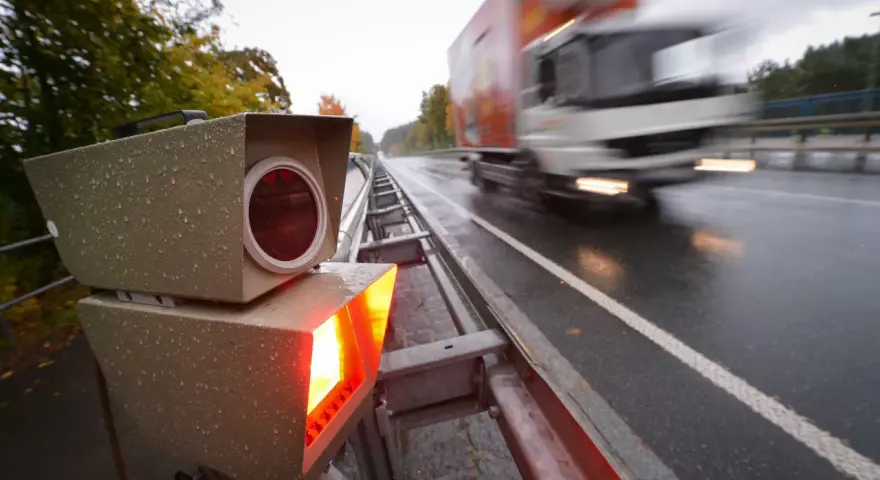 Blitzlicht erhellt die nasse Fahrbahn. Ein LKW rast vorbei. Das Zeugnisverweigerungsrecht bei Blitzern ist ein Thema für Fahrer.