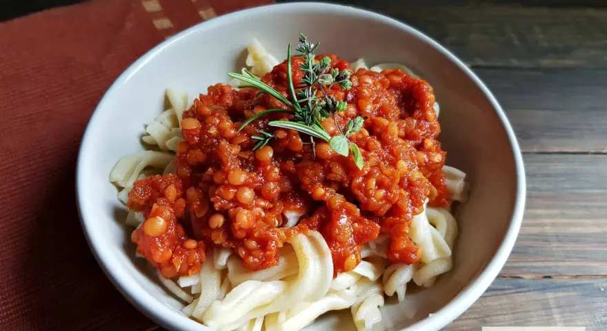 Herzhafte Linsen Bolognese auf Bandnudeln, garniert mit frischen Kräutern. Ein köstliches vegetarisches Gericht.