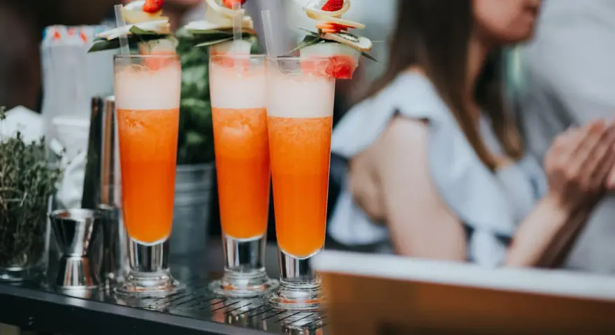 Orzeźwiający drink dla kobiet, ozdobiony owocami i listkami, gotowy do podania na letnim przyjęciu.