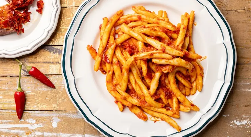Piatto di pasta con nduja e peperoncini rossi, un classico saporito.