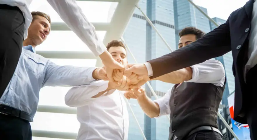 Un gruppo di uomini d'affari unisce i pugni, mostrando le loro caratteristiche personali di unità e determinazione.