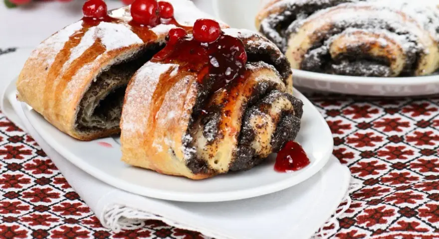 Saftige Mohnschnecken, verziert mit Kirschen und Puderzucker. Ein Genuss, der an die süßen Momente einer Schwangerschaft erinnert.