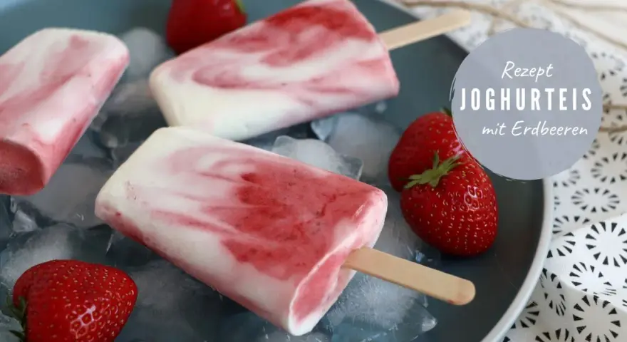 Erfrischendes Erdbeereis am Stiel mit Joghurt und frischen Erdbeeren auf Eiswürfeln.