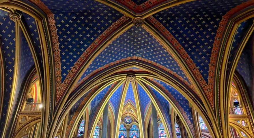 Techo abovedado de la Sainte-Chapelle, con intrincados detalles dorados y un cielo azul estrellado.