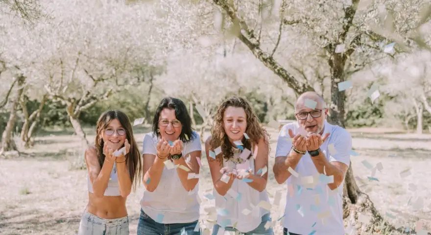 Photographie lifestyle : une famille lance des confettis sous des arbres fleuris, un moment de joie capturé.