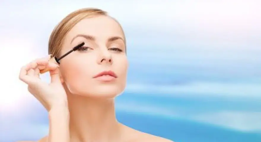 Une femme applique du mascara sur ses cils. Apprendre comment mettre du mascara pour un regard intense.