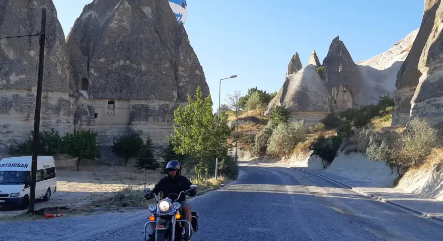 Niesamowita podróż motocyklem przez Kapadocję w Turcji. W tle widać latający balon i skalne formacje.