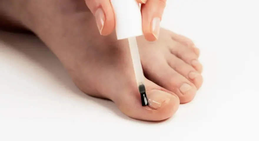 Application d'un soin transparent sur un ongle abîmé pour le protéger et le renforcer.