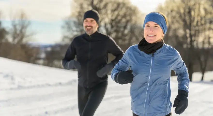 Ein Paar genießt das Laufen im Winter. Sie tragen passende Winterkleidung, um sich warm zu halten.