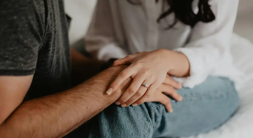Mains jointes, une bague orne le doigt de la femme, symbole de l'effet boomerang en amour : ce qui est donné revient toujours.