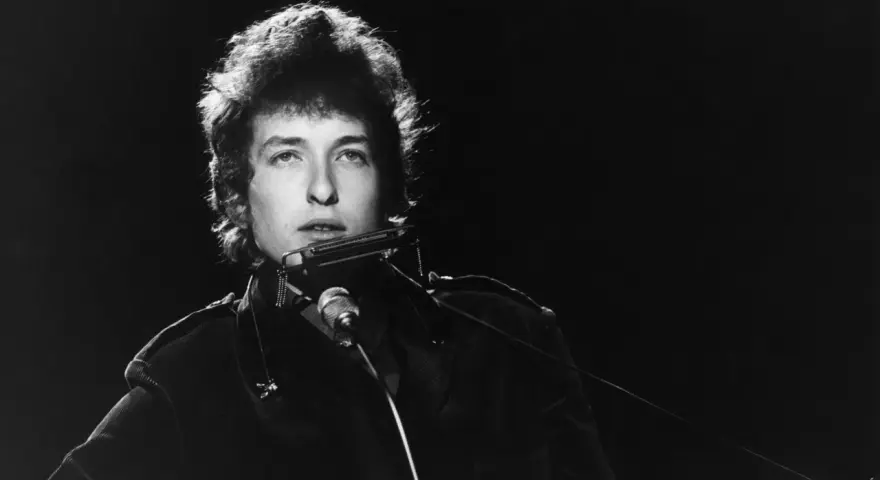 Bob Dylan spielt Mundharmonika, ein wahrer "rolling stone" auf der Bühne, mit seinem charakteristischen Blick.