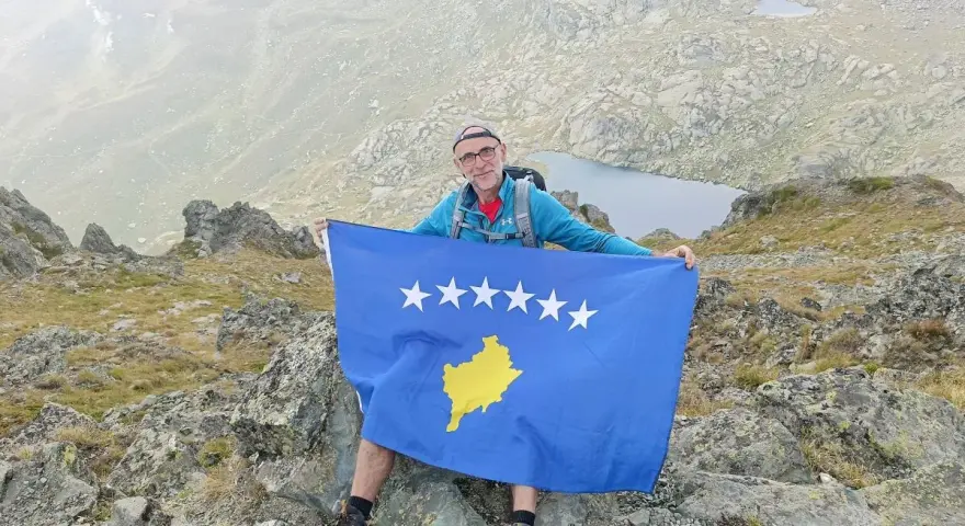 Mężczyzna z flagą najmłodszego państwa Europy, Kosowa, na szczycie góry.