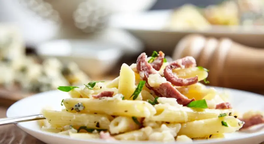 Piatto di pasta porri e salsiccia, cremoso e saporito, con pezzetti di formaggio e erbe fresche.