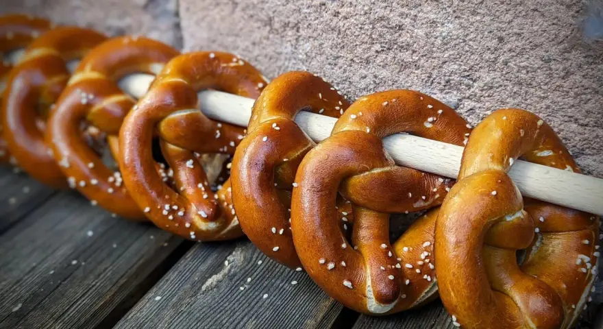 Frisch gebackene Brezeln, perfekt für ein Laugengebäck Rezept. Mit grobem Salz bestreut, liegen sie auf Holzbrettern.