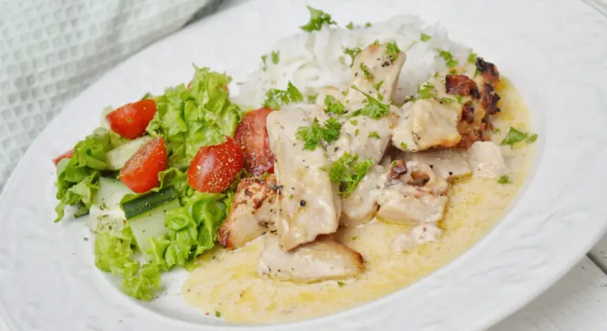 En krämig kycklinggryta med bacon, serverad med ris och en fräsch sallad.