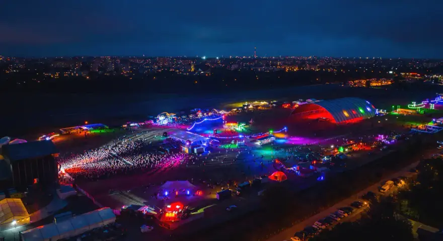 Nocne, kolorowe światła rozświetlają teren festiwalu na powietrzu. Tłumy bawią się pod wielkim, podświetlonym namiotem i na otwartych scenach.