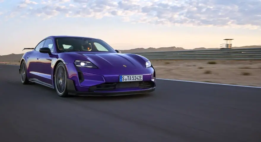 Fioletowe Porsche Taycan na torze wyścigowym podczas zachodu słońca.