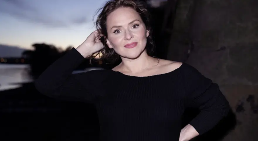 Emiliana Torrini, la chanteuse, pose au crépuscule près de l'eau, une main dans ses cheveux.