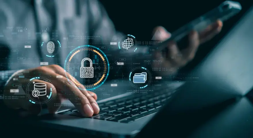 Manos sobre teclado de laptop, con iconos de seguridad digital: candado, huella, base de datos, globo terráqueo. Esto ilustra qué es la seguridad informática.