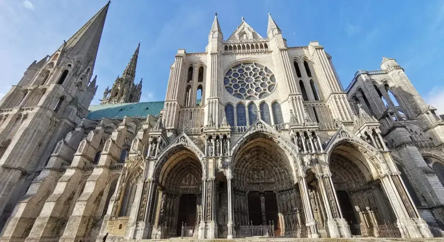The magnificent Chartres Cathedral, with its iconic rose window and soaring spires, stands majestically against a clear blue sky.