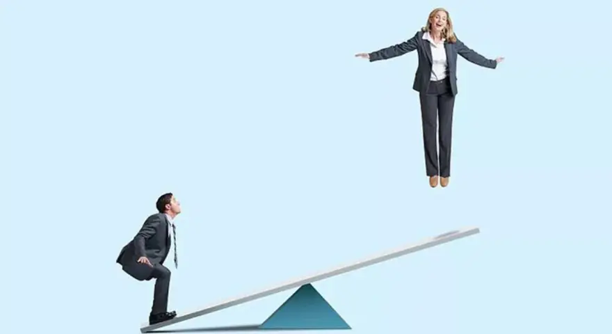 Un homme en costume sur une bascule regarde une femme en l'air. Un devoir de secours pour la faire descendre ?