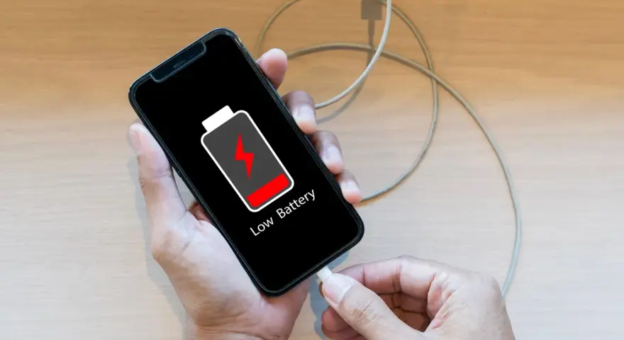 En person kopplar in sin mobil för att ladda mobilen på natten. Batteriikonen visar låg nivå.