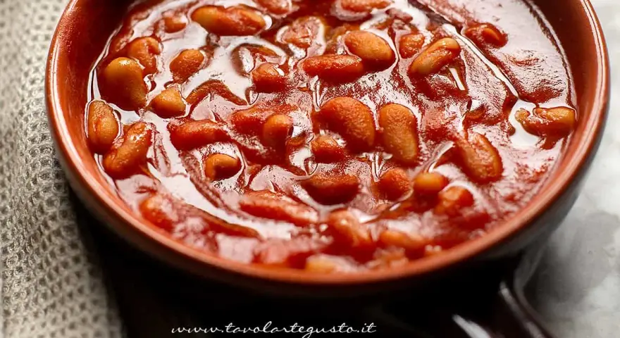 Un primo piano di fagioli all'uccelletto in una ciotola di terracotta, un classico delle ricette italiane.