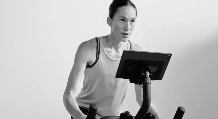 Focused woman powering through a hiit cycle workout on a stationary bike, her muscles engaged.