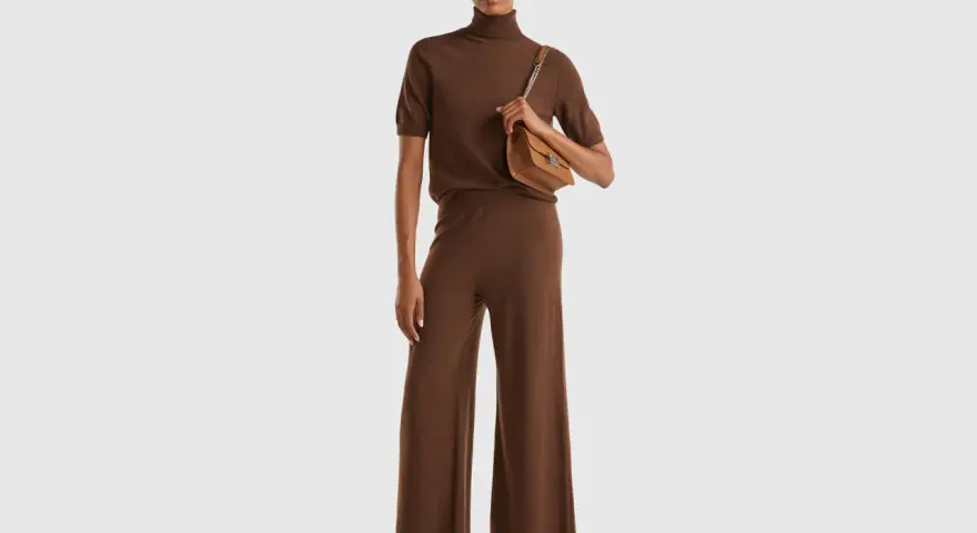 Mujer con conjunto marrón de cuello alto y pantalón ancho, bolso camel. Colores que combinan con el marrón, como el camel, resaltan la elegancia.