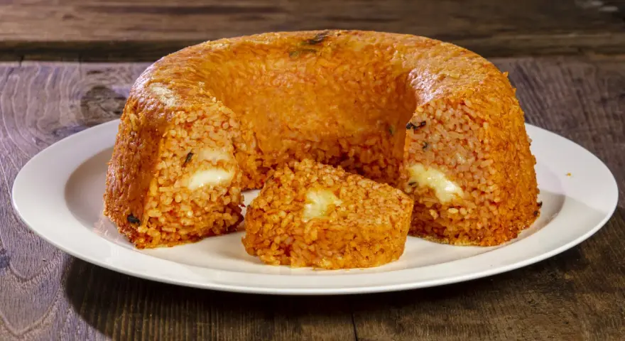 Un invitante timballo di riso, dorato e ripieno di formaggio filante, pronto per essere gustato.