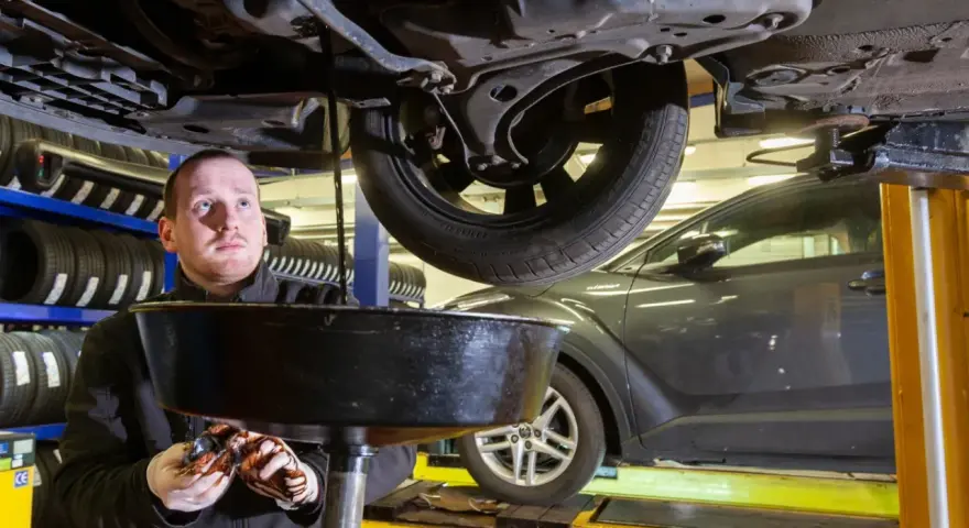 Mechanik spuszcza zużyty olej z samochodu. Zastanawiasz się, ile trwa wymiana oleju i filtrów?