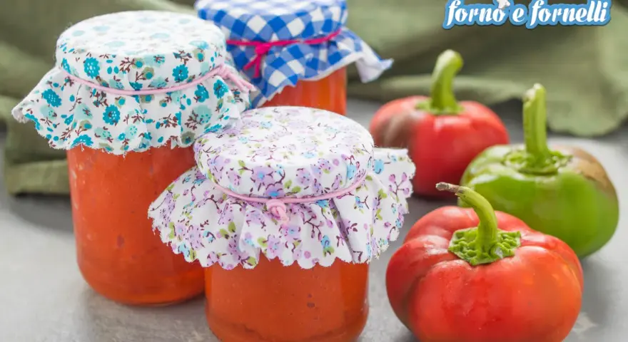 Barattoli di crema di peperoni fatti in casa, con peperoni freschi sullo sfondo.