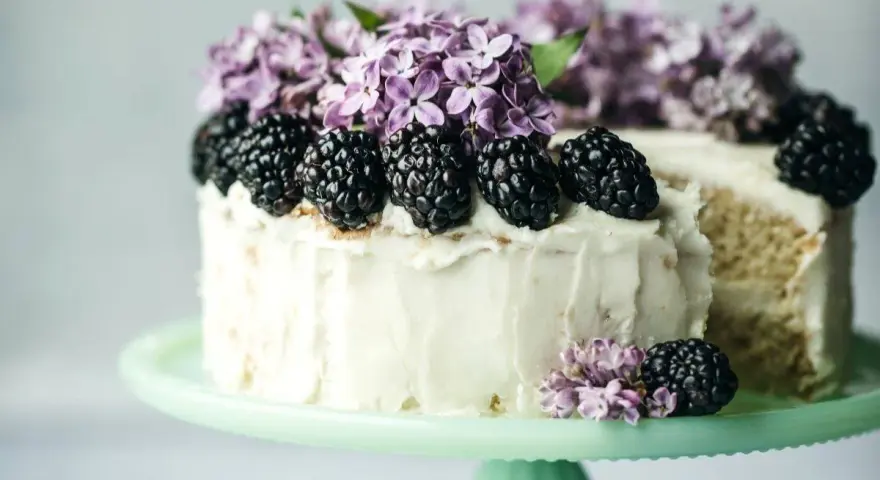 Biały tort z jeżynami i bzem, idealny przykład najmodniejszych smaków tortów.