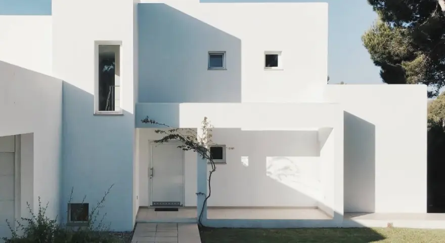 Fachada blanca moderna con sombras marcadas. La mejor pintura para fachadas exteriores protege y embellece esta arquitectura minimalista.