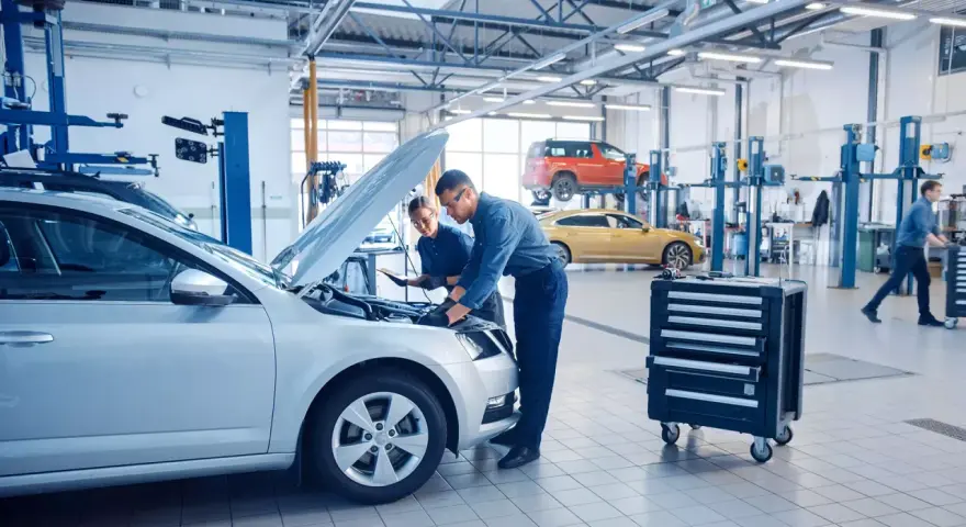 Mechanicy badają silnik srebrnego auta, szukając objawów uszkodzonego sterownika LPG.