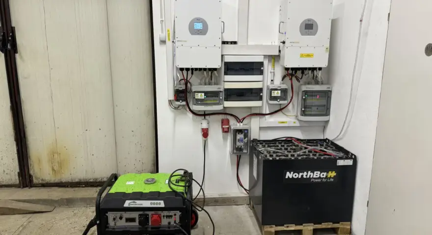 Instalacja fotowoltaiczna z falownikami, akumulatorami i agregatem prądotwórczym. System zapewnia niezawodne zasilanie.