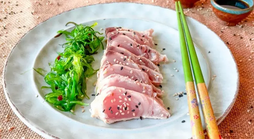 Tataki de bonito, finas lonchas de pescado crudo con semillas de sésamo, acompañadas de ensalada de algas.