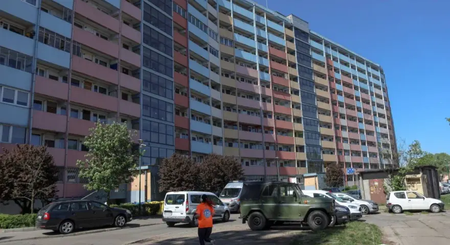 Długi, wielopiętrowy blok mieszkalny, prawdopodobnie najdłuższy blok w Polsce, z kolorowymi balkonami i oknami, na tle błękitnego nieba.
