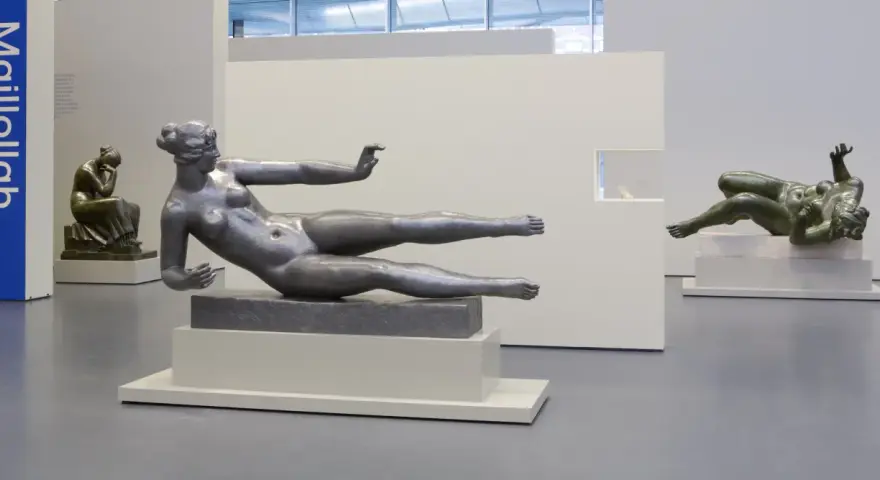 Exposition d'œuvres d'art de Aristide Maillol : sculptures de femmes nues en bronze et en métal, dans un musée.