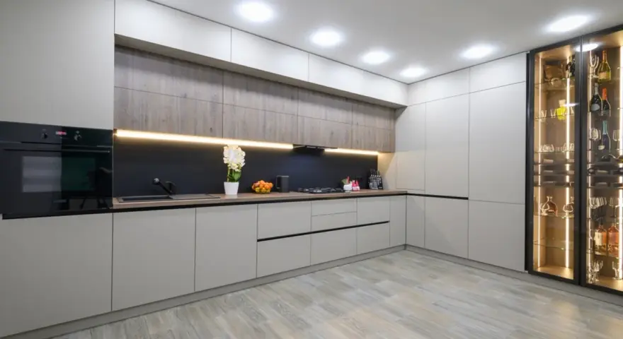 Cocina moderna con armarios grises y vitrina iluminada. El suelo de madera clara es perfecto para suelos para cocinas sin obras, aportando calidez y estilo.