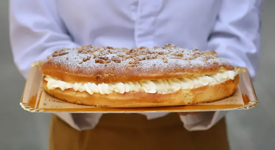 Deliciosa coca de San Juan rellena de crema, cubierta con azúcar glas y trocitos crujientes. ¡Perfecta para celebrar!